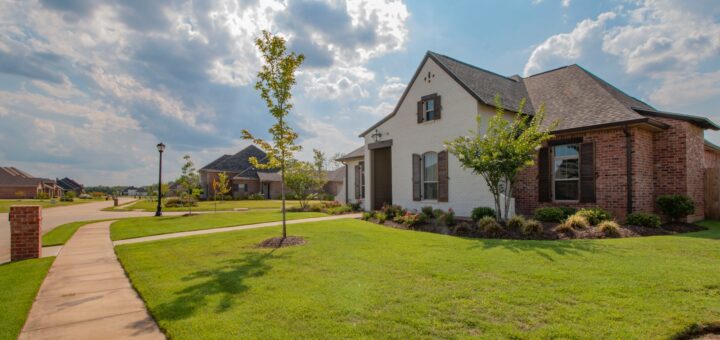 white and brown house near green grass field under white clouds and blue sky during daytime